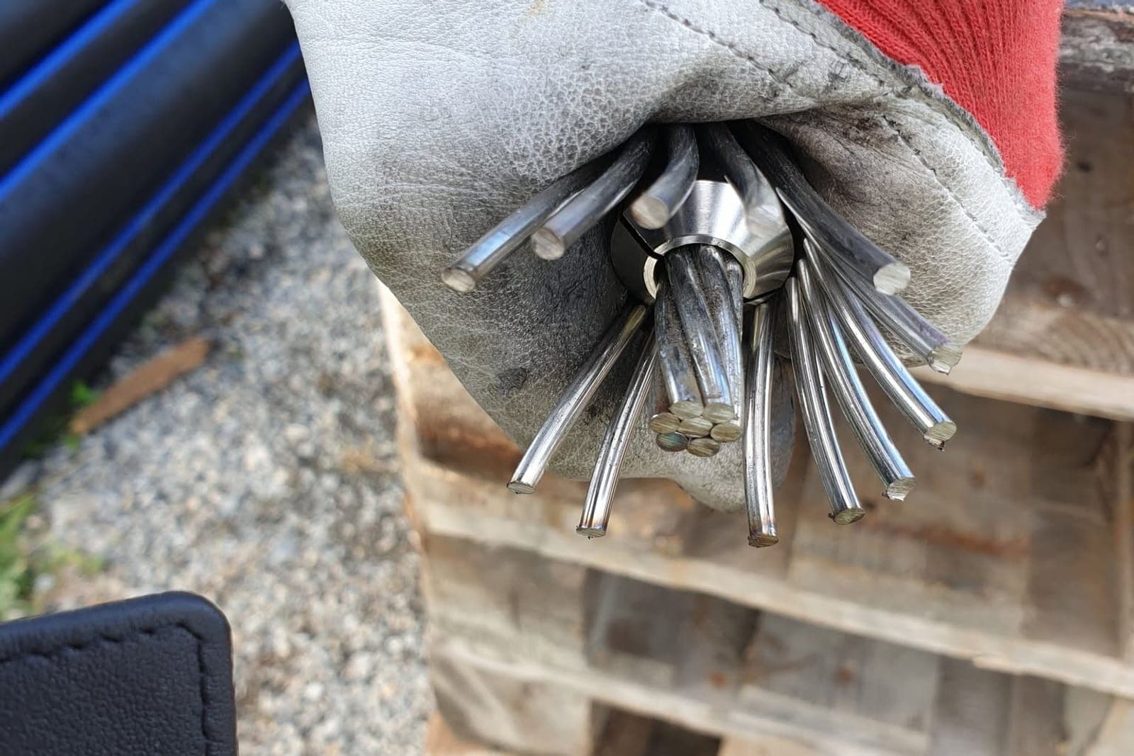 Hånd i arbeidshanske holder tauenden med kordelene viftet ut rundt kjeglen på en wiresocket før støping