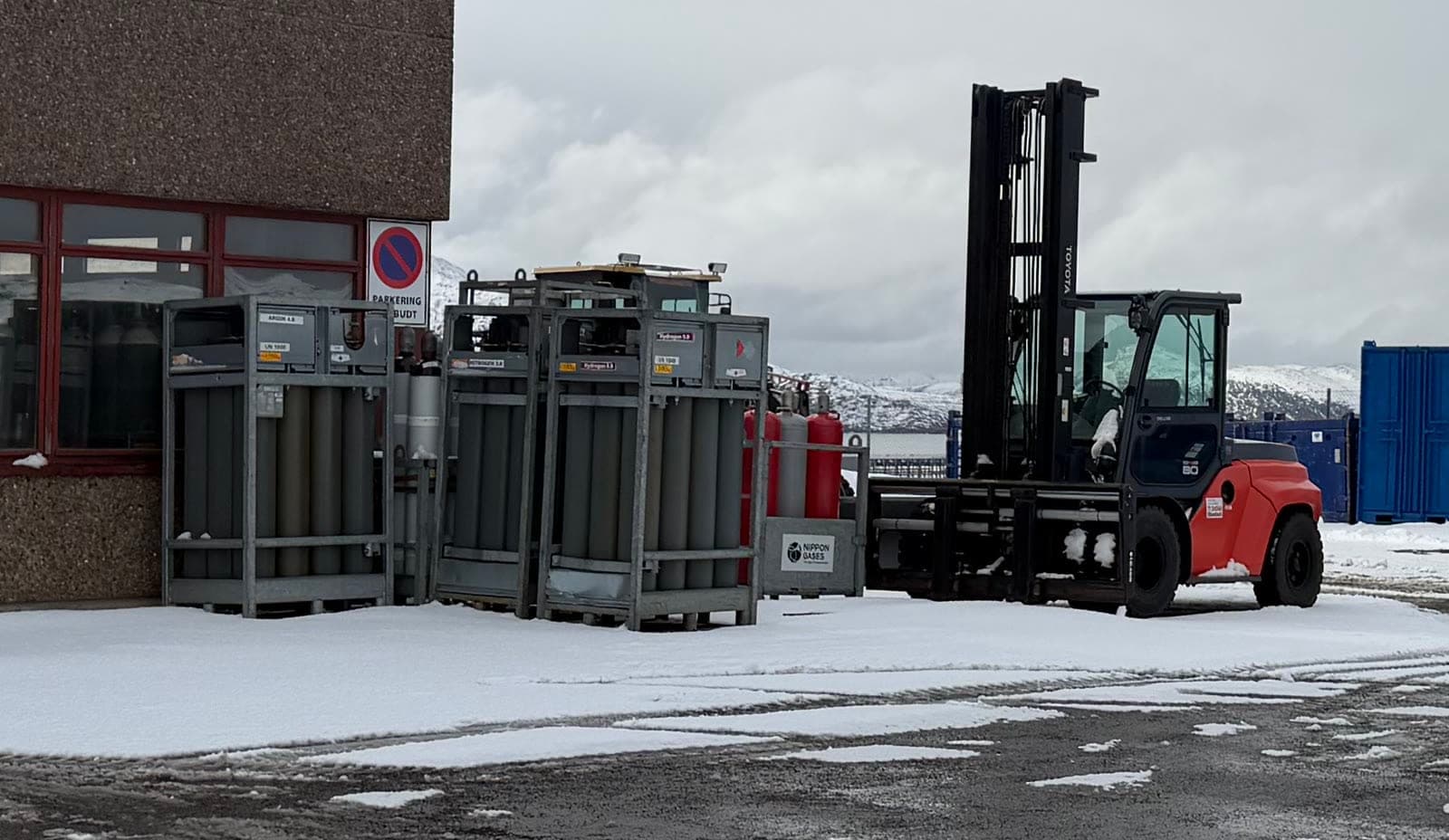 Gassflasker i galvaniserte rack utenfor lageret i Rypefjord, med truck og snø på plassen