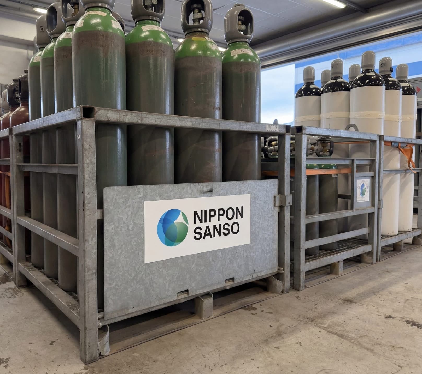 Gassflasker i galvaniserte stålrack merket Nippon Sanso inne på gasslageret