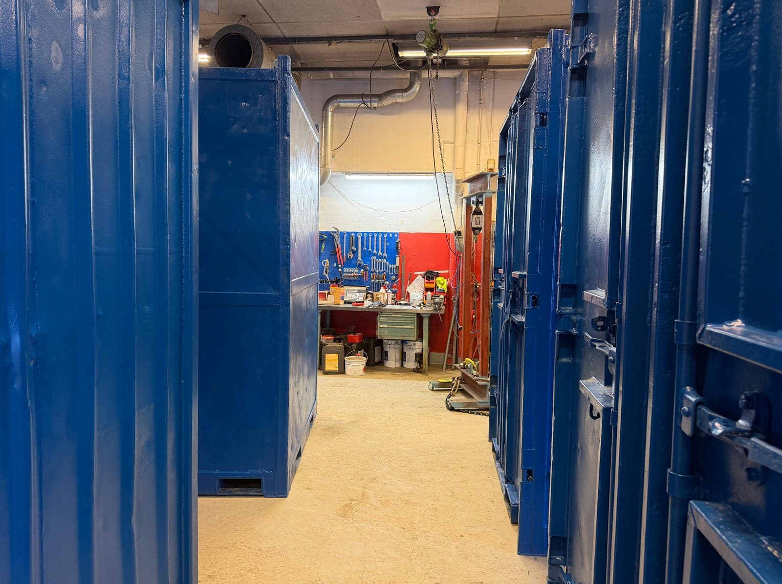 Blålakkerte offshorecontainere inne i containerverkstedet